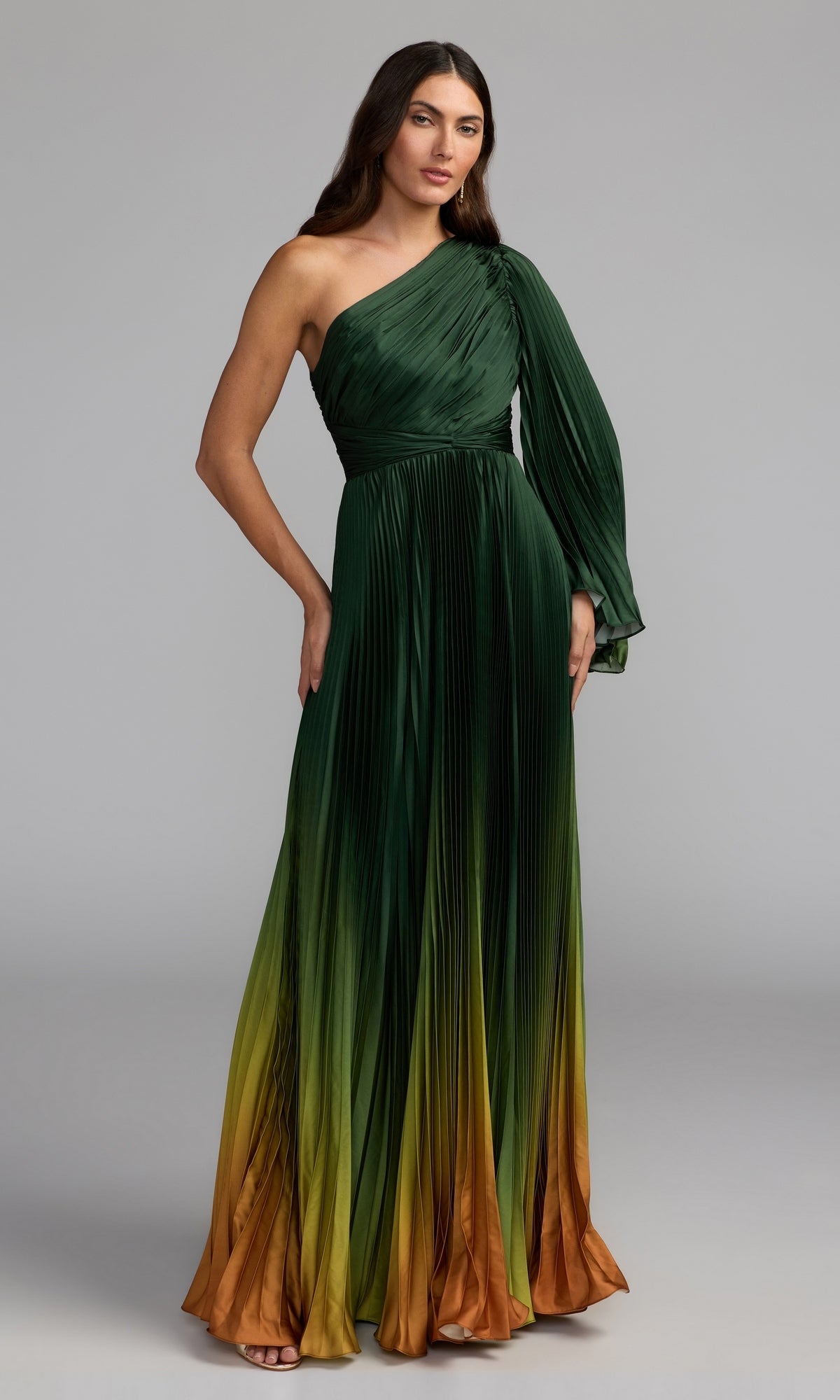 A woman stands against a plain gray background, wearing the Mac Duggal 49903 One-Shoulder Ombre Formal Dress—a pleated evening gown in a green ombre hue.